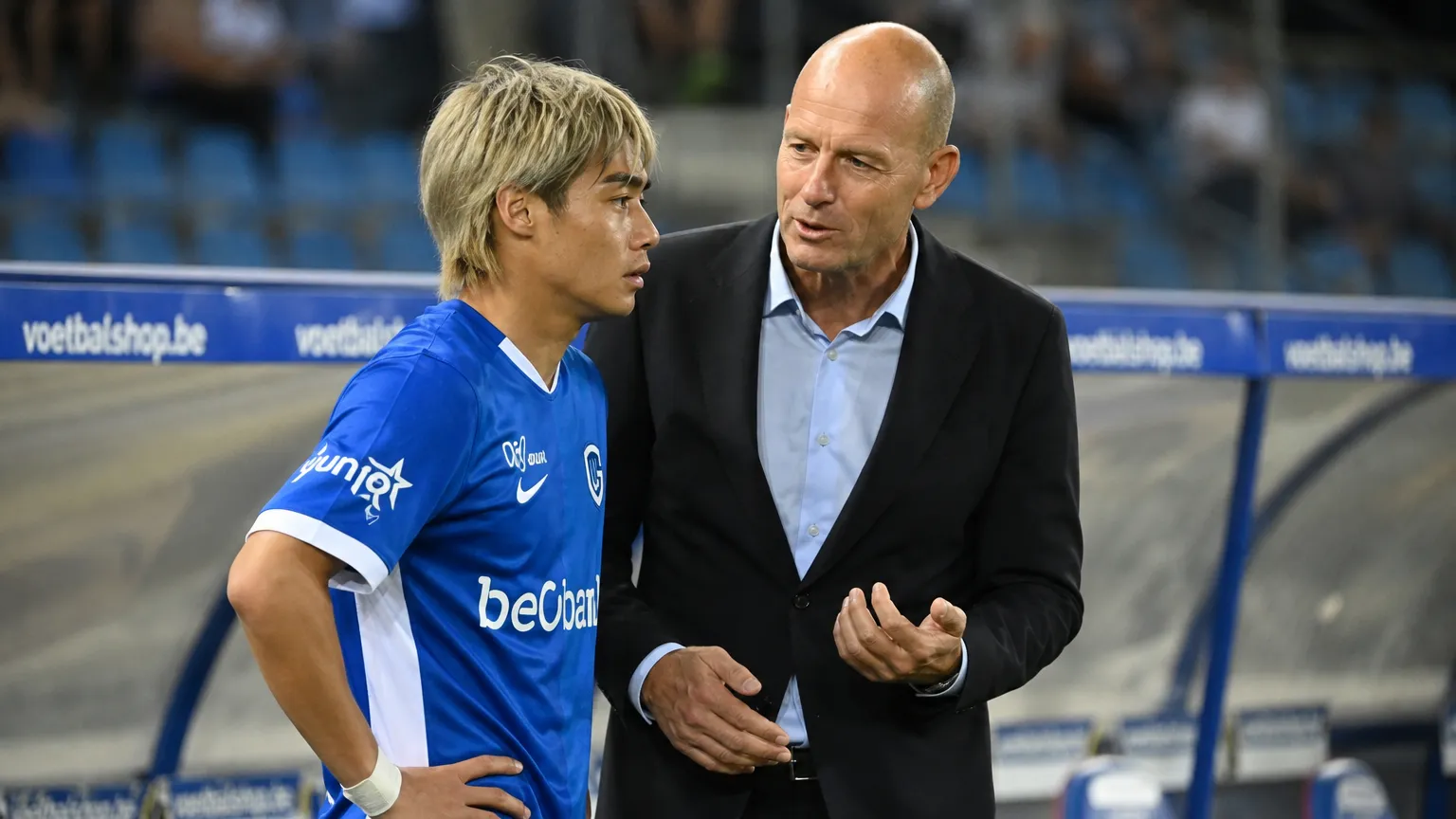 Jess Thorup staat met een Genk-speler langs de zijlijn voor een wedstrijd.