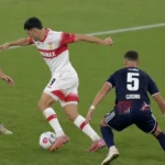 Voetballers van Stuttgart en Köln in duel om de bal op het veld.
