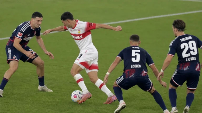 Voetballers van Stuttgart en Köln in duel om de bal op het veld.