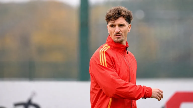 Thomas Meunier in een rode trainingsjas naast een oefenveld.