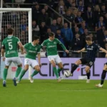 Voetballers van Lommel en Club Brugge in actie voor het doel tijdens de wedstrijd.
