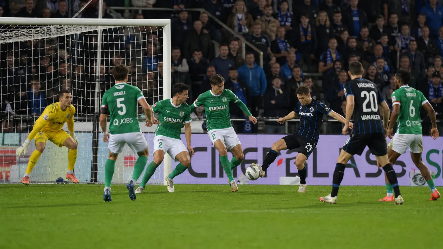 Voetballers van Lommel en Club Brugge in actie voor het doel tijdens de wedstrijd.