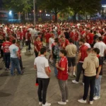 Een grote groep bezoekende supporters verzamelt zich buiten Sclessin voor een avondwedstrijd.