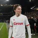 Ibe Hautekiet in het witte shirt van Standard aan de zijlijn van een stadion.
