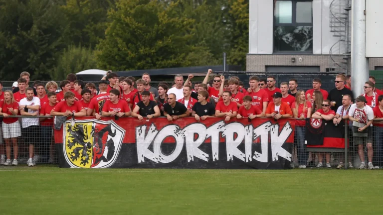 Kortrijkse supporters tonen een spandoek langs het trainingsveld.