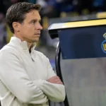 David Hubert staat rustig langs de zijlijn bij een dug-outpaneel met het embleem van Union SG.