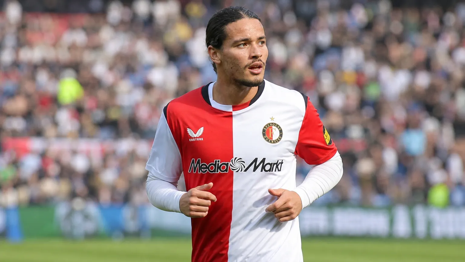 Anis Hadj Moussa in het shirt van Feyenoord op een voetbalveld.