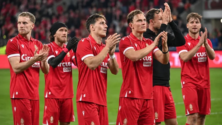 Een groep spelers van Standard in rode shirts op het veld na de wedstrijd.
