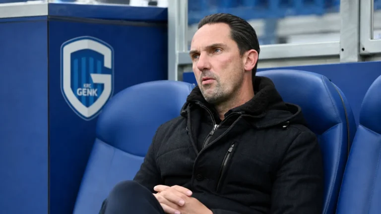 Dimitri De Condé zit in de Cegeka Arena met een KRC Genk-embleem op de vaste dug-outwand.