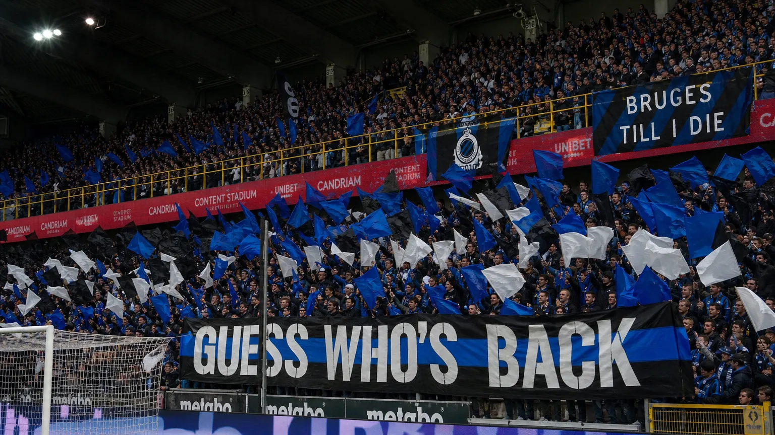 Collectieve Club Brugge-supporters met blauw-zwarte vlaggen op de tribune van Jan Breydel.