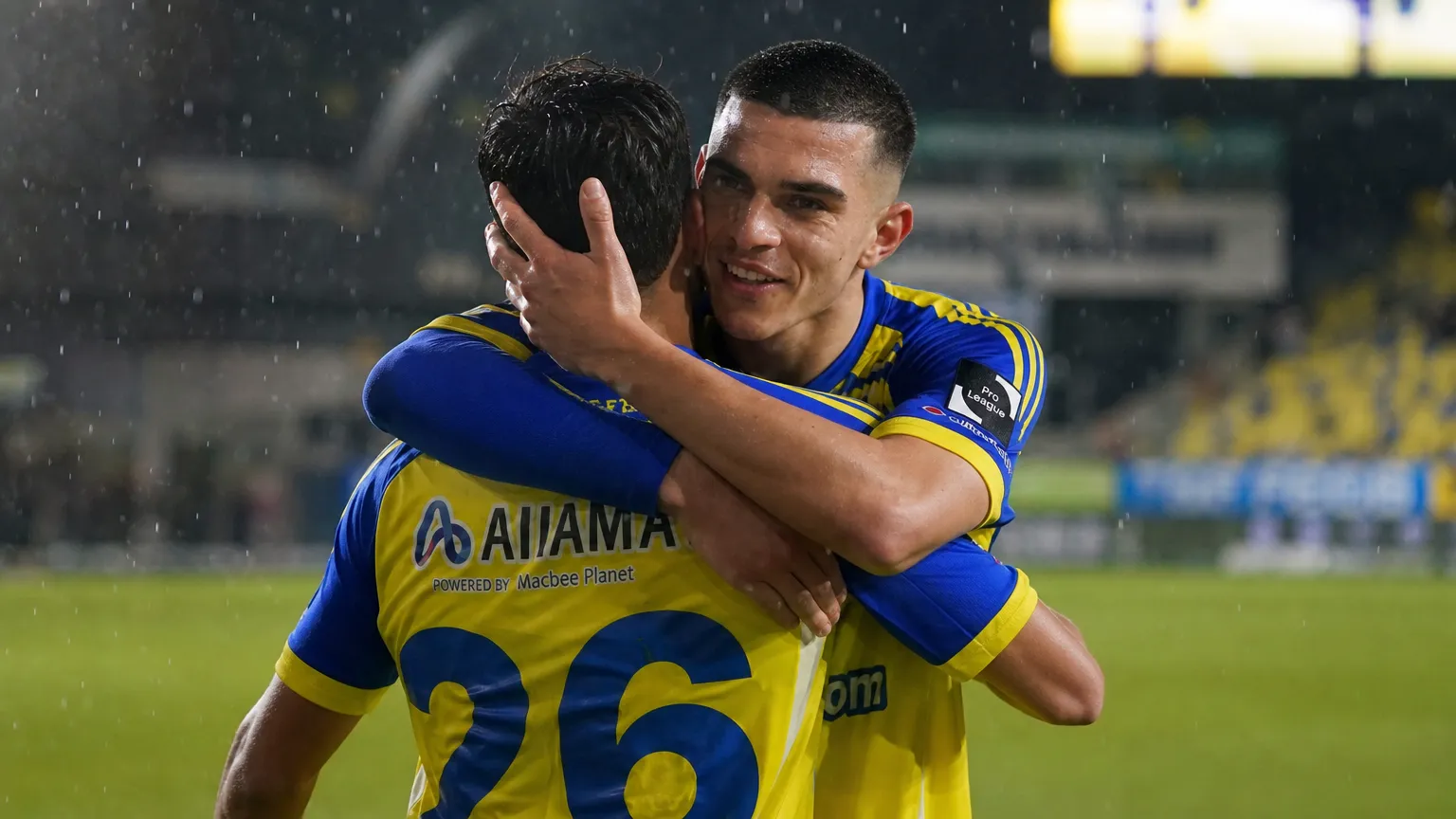 Ilias Sebaoui omhelst een ploegmaat van STVV op een regenachtig veld.