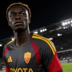 Robinio Vaz in een donker AS Roma-shirt onder de stadionverlichting.