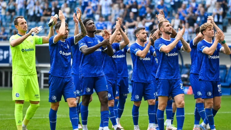 Een groep KAA Gent-spelers applaudisseert samen op het veld voor een tribune.