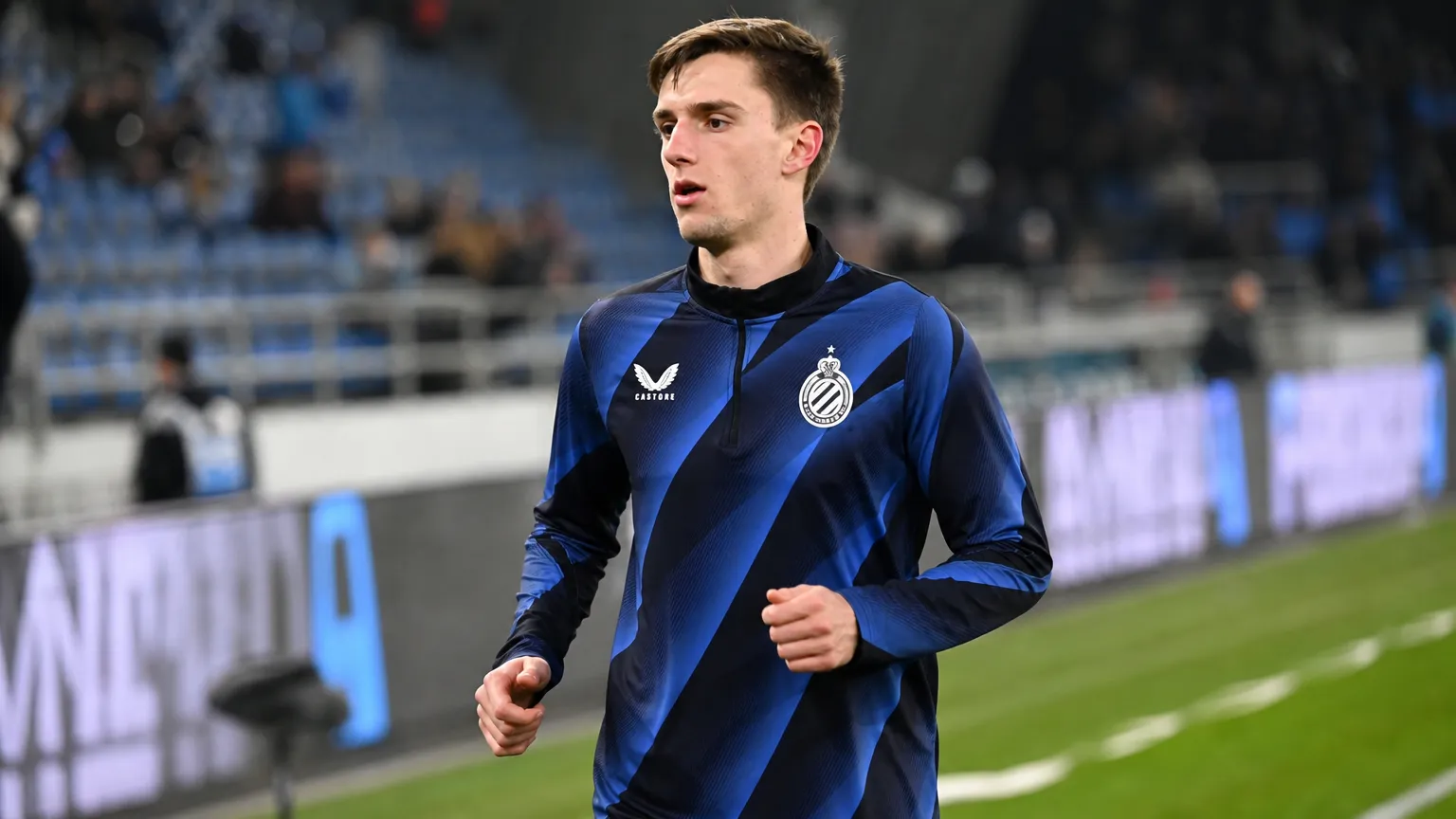Jorne Spileers warmt op in Club Brugge-kleding langs het veld.