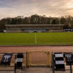 Het historische Warandestadion van KFC Diest met atletiekpiste, overdekte tribunes en zwart-witte clubaccenten.