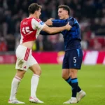 Twee voetballers in contrasterende wedstrijdtenues tijdens een gespannen moment op het veld.