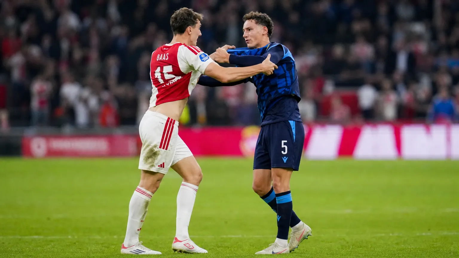Twee voetballers in contrasterende wedstrijdtenues tijdens een gespannen moment op het veld.
