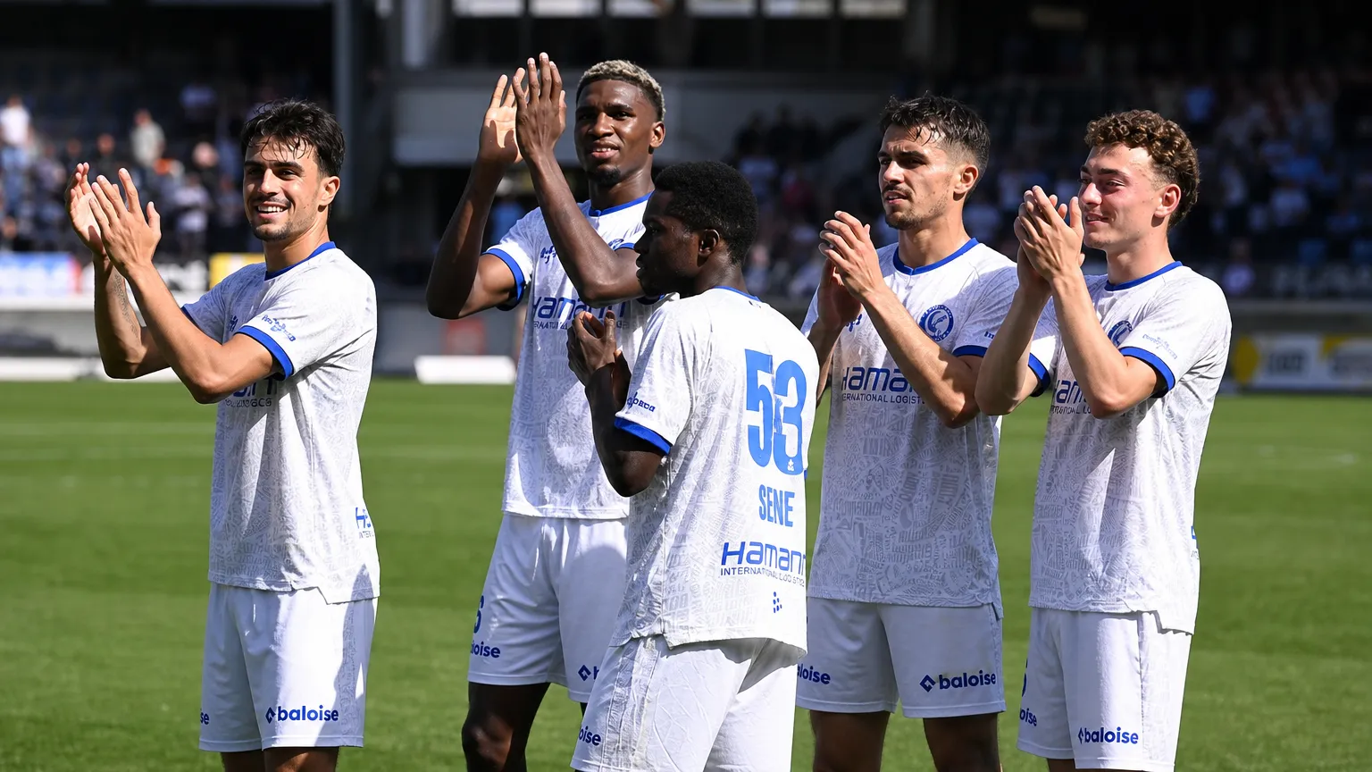 Een groep KAA Gent-spelers viert samen op het veld na de wedstrijd.
