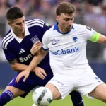 Twee spelers van Anderlecht en KRC Genk vechten om de bal tijdens een wedstrijd.