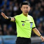 Yusuke Araki wijst tijdens een wedstrijd als scheidsrechter naar het veld.