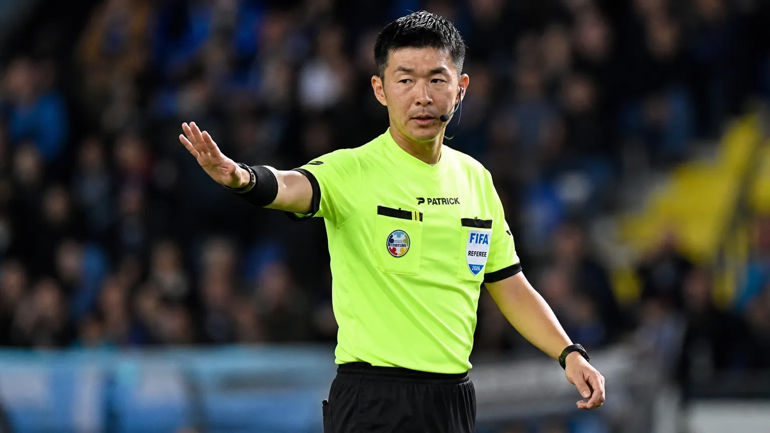 Yusuke Araki wijst tijdens een wedstrijd als scheidsrechter naar het veld.
