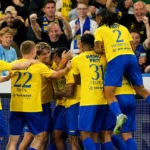 Beveren-spelers vieren samen een doelpunt aan de zijlijn tijdens een wedstrijd.