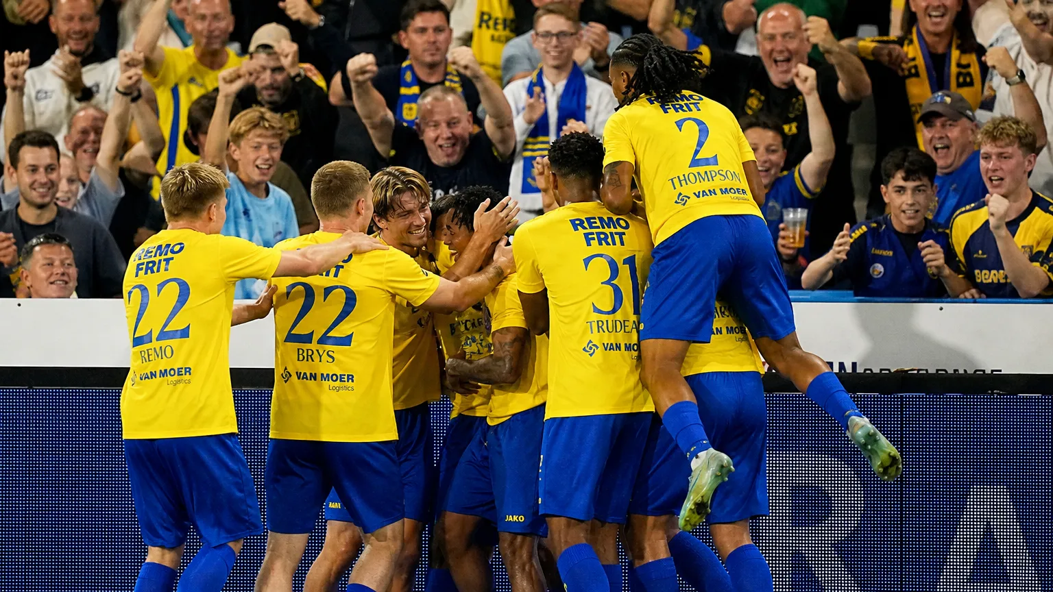 Beveren-spelers vieren samen een doelpunt aan de zijlijn tijdens een wedstrijd.