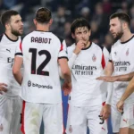 Een groep AC Milan-spelers in witte wedstrijdtenues verzamelt zich op het veld tijdens een Serie A-wedstrijd.