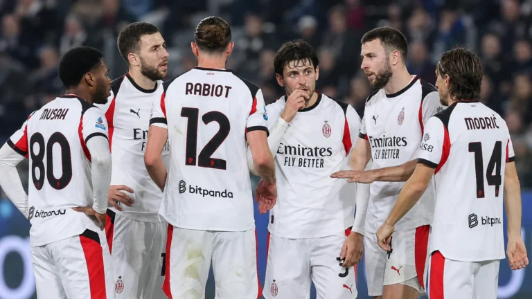 Een groep AC Milan-spelers in witte wedstrijdtenues verzamelt zich op het veld tijdens een Serie A-wedstrijd.