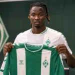 Moussa N’Diaye poseert met een Werder Bremen-shirt tijdens een officiële clubpresentatie.