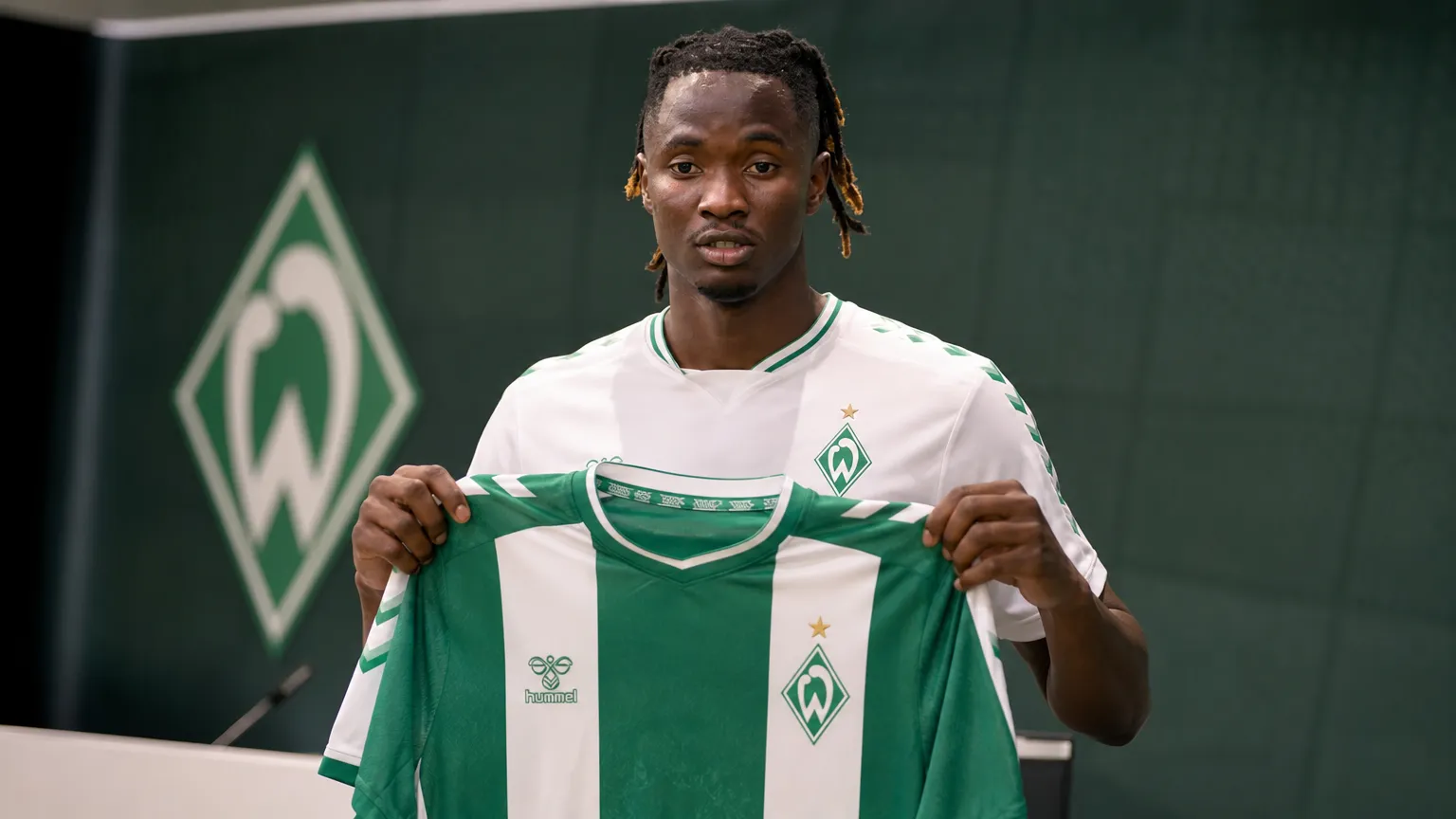 Moussa N’Diaye poseert met een Werder Bremen-shirt tijdens een officiële clubpresentatie.