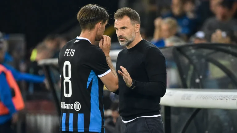 Een speler van Club Brugge overlegt langs de zijlijn met een staflid.