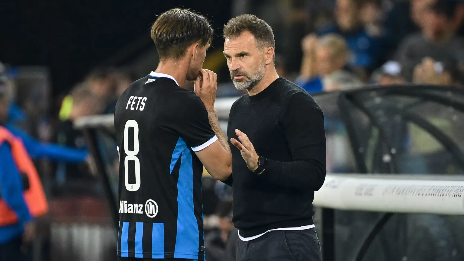 Een speler van Club Brugge overlegt langs de zijlijn met een staflid.