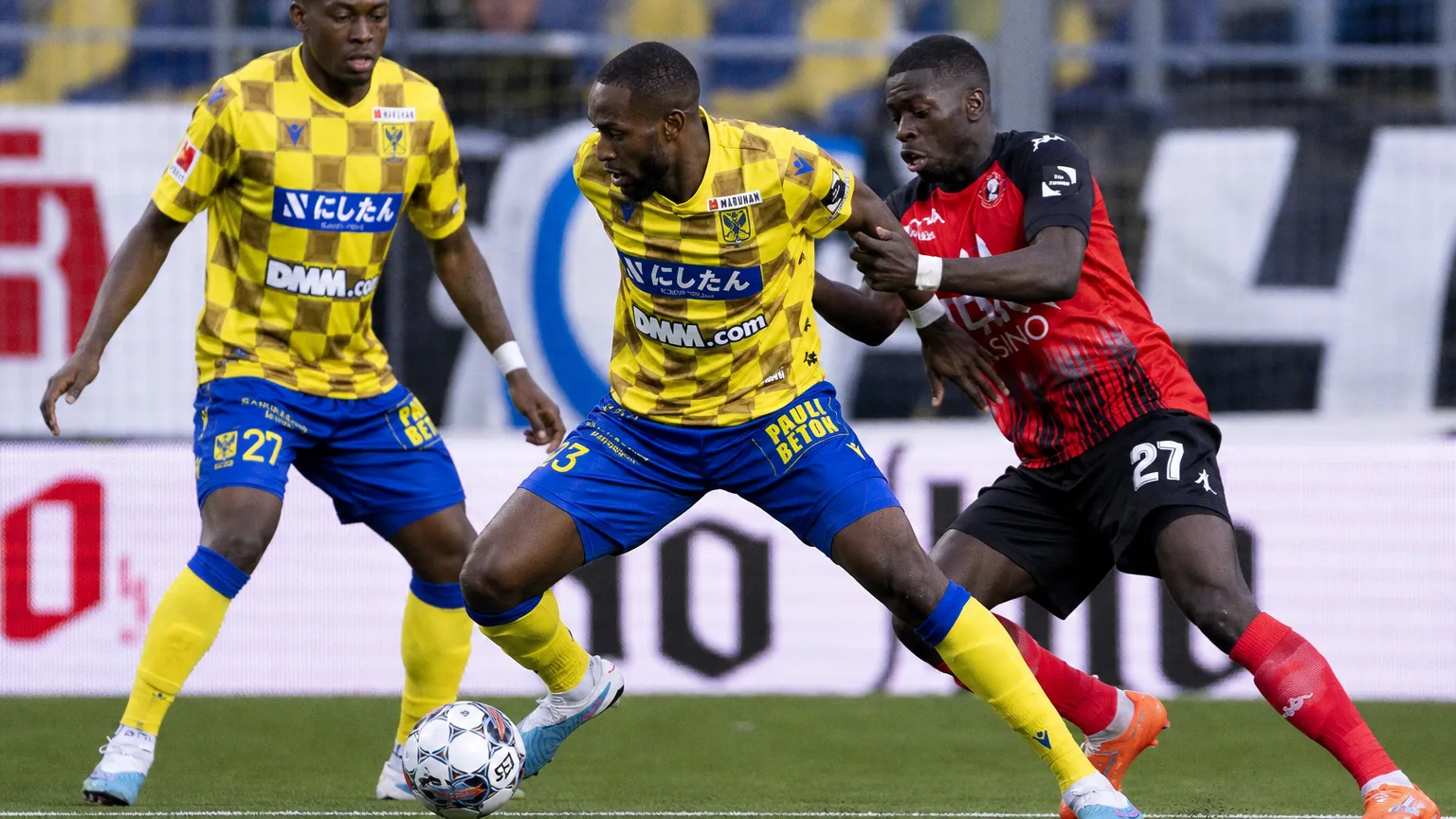 STVV-spelers in geel-blauwe tenues in een duel om de bal.