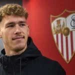 Lucas Stassin in een donkere trainingsjas in de mediazone van Sevilla.