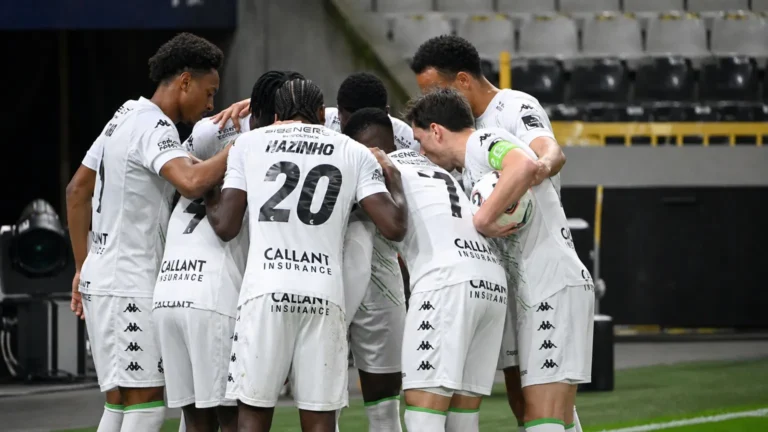 Een groep spelers van Cercle Brugge in witte wedstrijdtenues vormt een huddle op het veld.