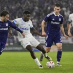 Spelers van Anderlecht en Genk strijden in de regen om de bal.