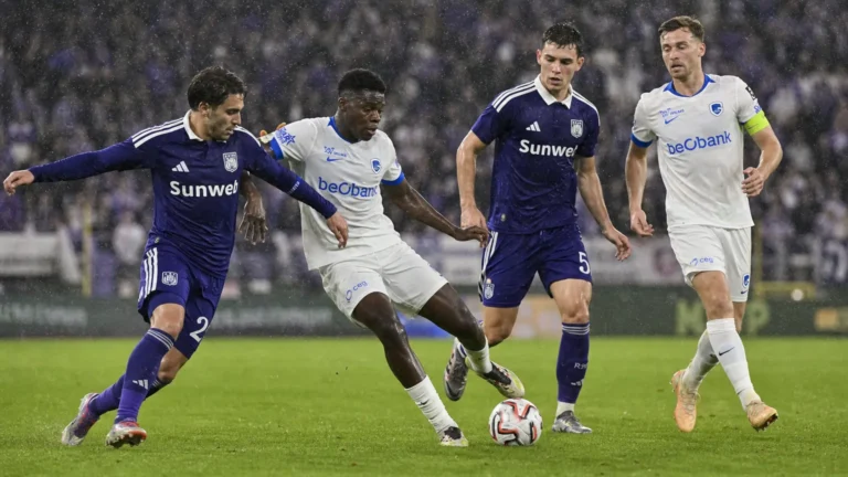 Spelers van Anderlecht en Genk strijden in de regen om de bal.