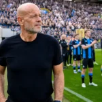 Bart Verhaeghe staat op de grasrand van het Jan Breydelstadion met Club Brugge-spelers op de achtergrond.