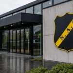 Het NAC Breda-clubembleem op een vaste gevelplaat aan een lege ingang.