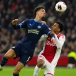 Twee voetballers strijden om de bal tijdens Ajax-PSV.