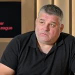 Philippe Albert tijdens een analysegesprek in een voetbalstudio met een Jupiler Pro League-paneel aan de muur.