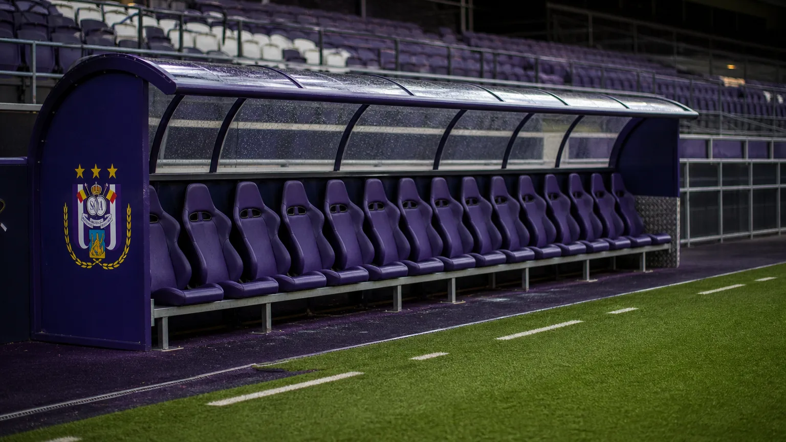 Lege dug-out van Anderlecht na de wedstrijd met een clubembleem op het zijpaneel.