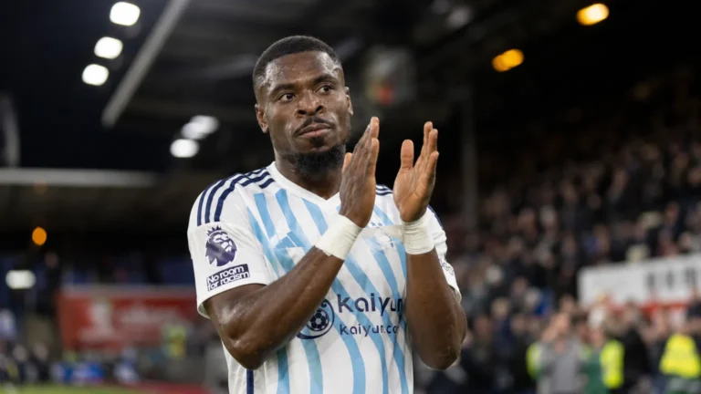 Serge Aurier applaudisseert in een wit shirt met lichtblauwe strepen.
