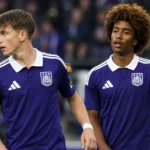 Twee voetballers in paarse shirts tijdens een neutraal wedstrijdmoment.