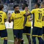 Een groep Union-spelers viert samen op het veld in gele wedstrijdtenues.
