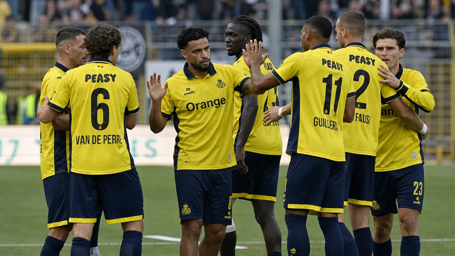 Een groep Union-spelers viert samen op het veld in gele wedstrijdtenues.