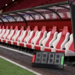 Lege spelersbank van Ajax met een digitaal wisselbord naast het veld.
