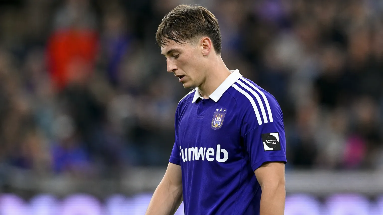 Een Anderlecht-speler reageert teleurgesteld op het veld in een paars wedstrijdshirt.