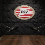 Lege podcaststudio met twee microfoons en een PSV-embleem op de wand.